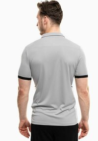 Graues Poloshirt mit kurzen Ärmeln, ausgestattet mit schwarzen Bündchen und einer eleganten, glatten Textur. Entworfen mit einem klassischen Kragen und minimalistischer Optik.