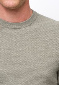 Maglione grigio chiaro a maglia con una superficie testurizzata e scollo rotondo. Il tessuto sembra morbido e leggermente elastico.
