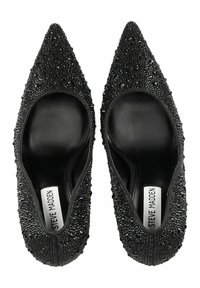 Tacones negros de punta afilada con un exterior texturizado que presenta pequeños adornos brillantes y un interior negro liso. Etiqueta de la marca visible en el interior.