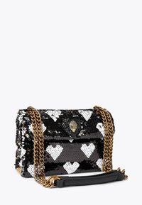 Borsa a tracolla con paillettes in bianco e nero con motivi a cuore, tracolla a catena dorata e chiusura decorativa. Forma strutturata con superficie testurizzata.