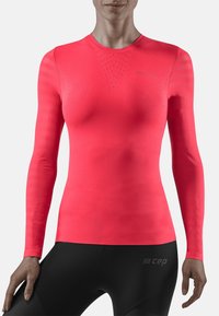 Figurbetontes Langarmhemd in leuchtendem Pink, aus glattem Stoff mit strukturierten Einsätzen und dezentem Branding auf der Brust und am unteren Saum.