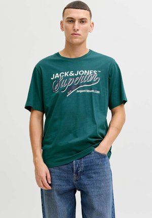 Green cotton T-shirt with short sleeves, featuring white and navy text: "JACK & JONES Superior Regent Street, LDN." Simple crew neck design.