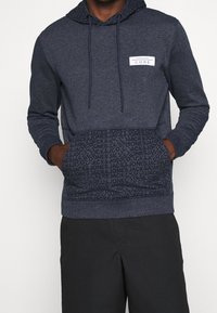 Felpa con cappuccio blu navy realizzata in tessuto morbido, dotata di tasca decorata con logo "JACK & JONES" e cappuccio regolabile con cordino.