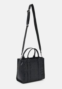 Musta käsilaukku, jossa on teksturoitu kuvio, kaksinkertaiset yläkahvat ja säädettävä olkahihna. Rakenteeltaan suorakaiteen muotoinen ja kiiltäväpintainen.