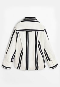 Chemise boutonnée rayée blanche avec des rayures verticales noires. Présente un col classique et des manches longues avec des poignets contrastants.