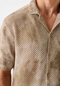 Korte mouwen, overhemd met knoopsluiting, gemaakt van beige meshstof met een ruitpatroon en een kraag, voorzien van kleine, ronde knopen.