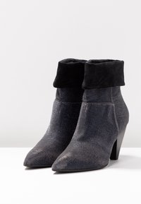 Bottes de cheville à bout pointu avec une tige texturée gris foncé et une bordure en daim noir, présentant un talon empilé et un éclat métallique.