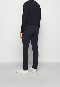 Granatowe bawełniane spodnie o wąskim kroju i delikatnej fakturze, połączone z białymi trampkami. Posiadają kieszenie z tyłu oraz średni stan.