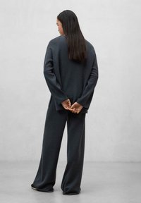 Mörkgrå ulltröja med vida ärmar, matchad med vida byxor. Enkel design, enfärgad och mjuk textur.