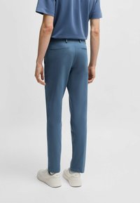 Men's blue soft fabric pants with a slim fit, featuring back pockets and a smooth texture, paired with white sneakers.