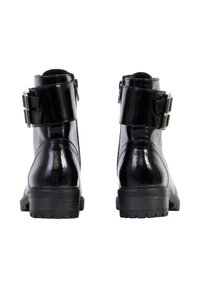 Botas de tobillo de charol negro con un acabado brillante, que cuentan con dos hebillas decorativas y una suela de goma texturizada.