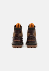 Brown leather and suede boots with a padded collar, orange lining, and sturdy treaded soles. Features contrasting stitching and metal hardware.