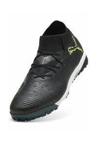 Botas de fútbol negras con parte superior sintética texturizada, collar de tobillo elástico, acentos verdes y suela para terreno firme. Cuenta con un sistema de cordones para un ajuste adecuado.