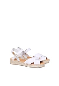 Bílé kožené sandály s křížovými pásky, espadrilková juteová podrážka a nastavitelným zámkem kolem kotníku. Hladký povrch, minimalistický design.