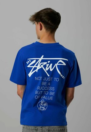 Camiseta de algodón azul con mangas cortas. Gran texto blanco en la parte posterior que dice "Esfuerzo" y frases motivacionales, acompañadas de un gráfico de dibujos animados.