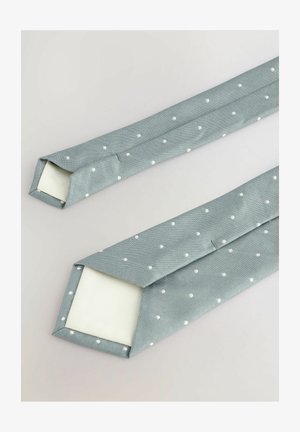 Strukturierte hellblaue Krawatte mit weißen Punkten, endend mit einem quadratischen Ende. Der Stoff hat ein glattes, gewebtes Aussehen.