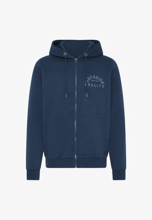 Blå hettegenser med glidelås og snorhette, myk stoff, ribbestrikkede mansjetter og nederkant, og teksten "SUPERIOR QUALITY" i hvitt på brystet.