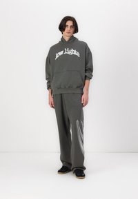 Hoodie cinza com o texto "low lights", combinado com calças de jogger cinzas a condizer com riscas brancas diagonais. O material parece suave e de corte descontraído.