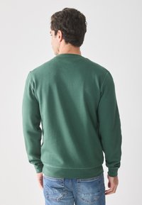 Grüne Sweatshirt aus weichem Material, mit rundem Halsausschnitt und gerippten Bündchen. Die Rückseite zeigt eine glatte Oberfläche ohne Muster.