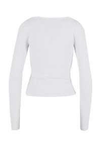 Valkoinen pitkähihoinen paita, joka on valmistettu sileästä kankaasta. Ominaisuuksiin kuuluu istuva siluetti, suora helma ja pyöreä pääntie. Minimimalistinen muotoilu ilman kuvioita.