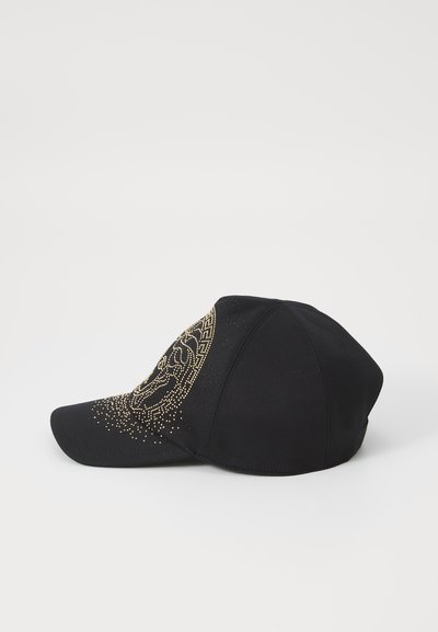 Svart keps i tyg med en böjd skärm och design med gyllene nitar. Framsidan har ett geometriskt mönster.