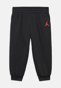 Μαύρες φόρμες με ελαστική ζώνη και μανσέτες. Διαθέτουν κόκκινο λογότυπο Jordan στο μηρό. Φτιαγμένες από μαλακό, υφασματώδη υλικό.