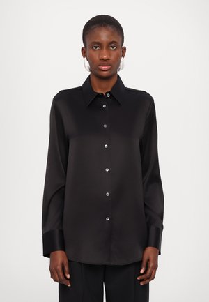 Black satin shirt with long sleeves, a collar, front button placket, and shiny button details. Smooth texture and relaxed fit.