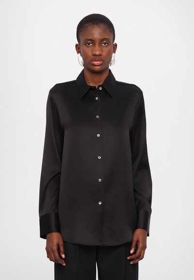 Chemise en satin noir avec des manches longues, un col, une patte de boutonnage à l'avant et des détails de boutons brillants. Texture lisse et coupe décontractée.