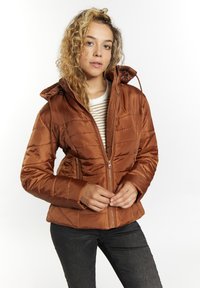 Brun isoleret hættejakke med kviltet design, frontlynlås og sidelommer. Båret over en stribet skjorte og parret med mørke bukser.