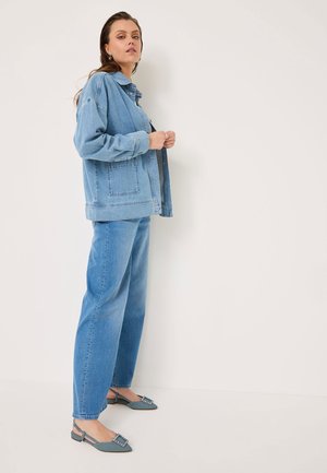 Lysblå denimjakke med en boxy pasform, to forlommer og knaplukning, parret med lysblå jeans med lige ben og grå slingback sko.