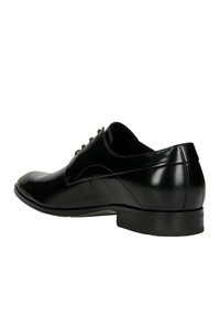 Scarpa da cerimonia nera in pelle con punta arrotondata, superficie liscia, cuciture decorative e tacco basso. Presenta un design classico con lacci.