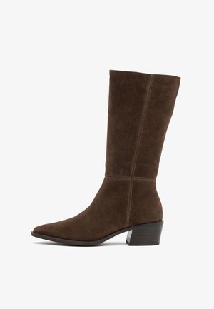 Ruskisat nahkaiset keskipitkät saappaat, joissa on teräväkärkinen muoto ja hieman levenevä korko. Saumayon yksityiskohdat kulkevat pystysuoraan ulkosyrjillä.