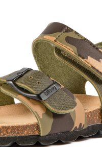 Sandales à motif camouflage avec des sangles ajustables, une fermeture par boucle, une doublure douce en suédine et une semelle en caoutchouc noir texturé.