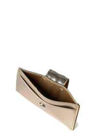 Cartera metálica dorada con cierre a presión, con textura suave, un solo compartimento y forro de tela en el interior.