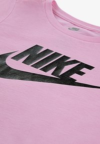Rosa bomull t-skjorte med en stor svart Nike-logo over brystet, rund hals og myk tekstur.