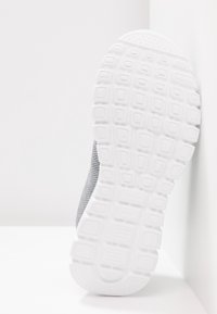 Chaussure de sport en maille grise avec une semelle en caoutchouc blanc présentant un design texturé et un motif rectangulaire pour une meilleure adhérence.