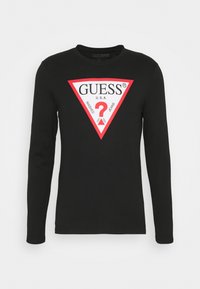 Schwarzes langärmeliges T-Shirt mit großem rotem dreieckigem Grafikdesign, das den Text "GUESS" und ein Fragezeichen zeigt, mit glatter Textur.