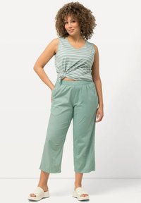 Ljusgrön ärmlös topp med vita ränder, knuten i midjan. Matchande lösa byxor i ankellängd. Bärs med vita plattformsandaler.