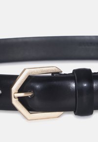 Cintura in pelle nera con finitura texture, fibbia esagonale dorata e una singola asola per il fermaglio. Design classico con diverse forature di regolazione.