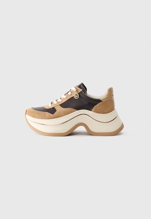 Baskets à plateforme épaisses en daim beige et cuir marron foncé avec lacets blancs et semelle blanche épaisse et incurvée.