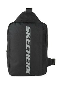 Mochila de tela negra con forma rectangular, que presenta un prominente logo gris de "SKECHERS" en posición vertical. Incluye un asa en la parte superior y una correa lateral.