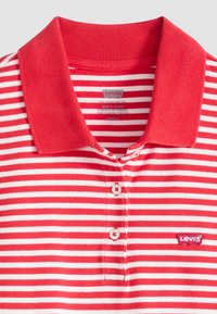 Polo rayé rouge et blanc avec un col texturé, une patte de boutonnage à trois boutons, et un petit logo Levi's sur la poitrine gauche.