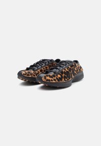Løveprikkede sneakers med sorte læderdetaljer, rund form, tekstureret overdel og orange gummisål med grebsdetaljer.
