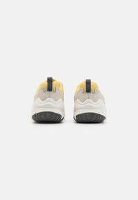 Teksturerte grå og gule sneakers med myk såle, bakre grepestropp og svart gummisåle. Rund design med lagdelte materialer.