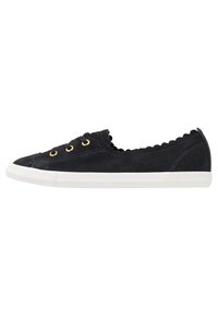 Musta samettinen sneaker scallop-reunojen, kullanväristen silmukoiden ja valkoisen kumipohjan kanssa. Matala profiili ja tasainen nauhakiinnitys.
