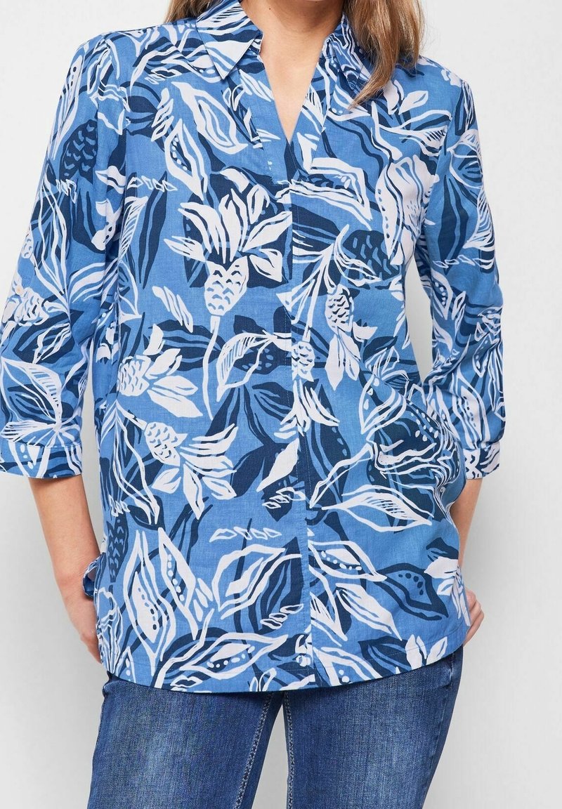 Blue button-up shirt with white floral patterns, 3/4 sleeves, and a collar. Made of lightweight fabric with a smooth texture.