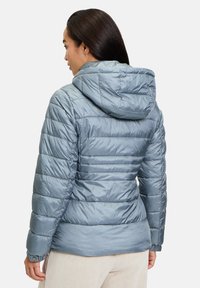 Giacca blu puffosa con cappuccio, caratterizzata da sezioni trapuntate orizzontali e polsini elasticizzati. Texture liscia e lucida con una silhouette aderente.
