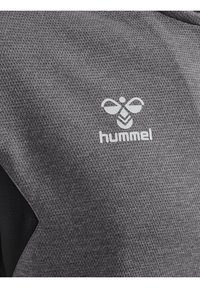 Grijs textuur atletiekshirt met zwarte accenten en een witte "hummel" logo met een bijontwerp. Het materiaal lijkt ademend en lichtgewicht te zijn.