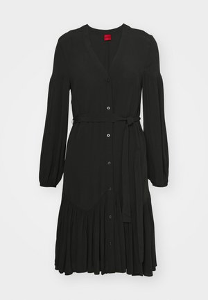 Rochie neagră dintr-un material ușor, cu decolteu în V, mâneci lungi, nasturi pe față, talie cu curea și un tiv evazat cu volane.