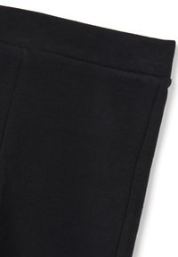 Leggings en tissu extensible noir avec une texture lisse, dotés d'une taille large et d'un design simple et sans coutures.